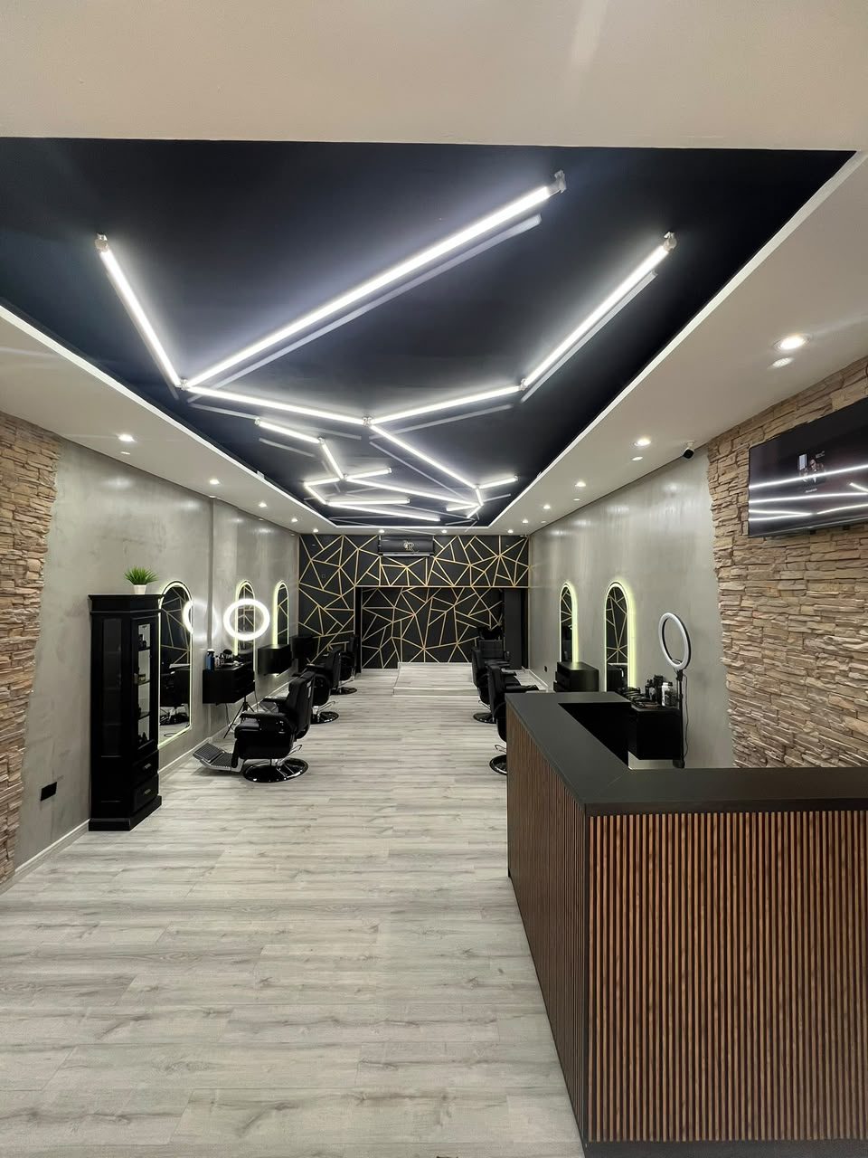 Interior de Royal Barbería sucursal Caamaño: salón con sillones de barbero, espejos y techo de neón